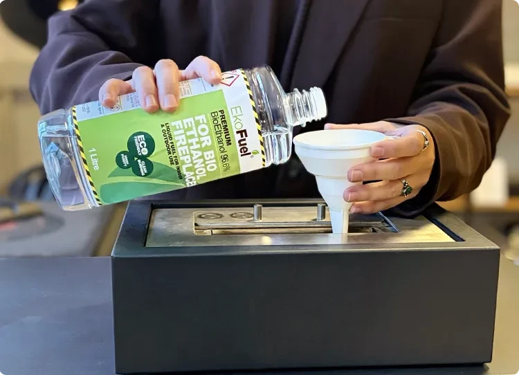 pouring bioethanol fuel in a burner with a plastic funnel