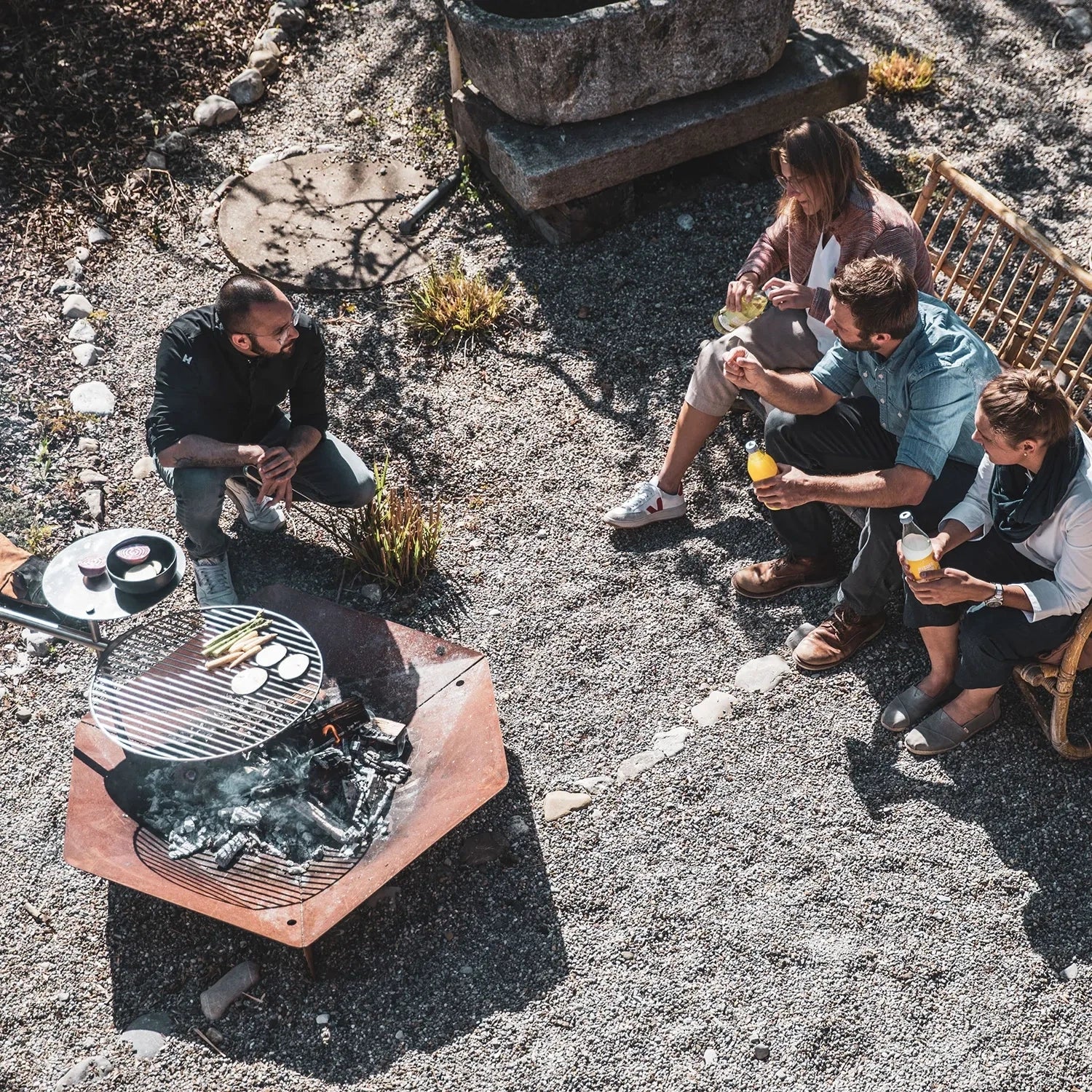 Höfats TRIPLE 120 Fire Pit in Corten Steel with burning logs, placed on a white surface.